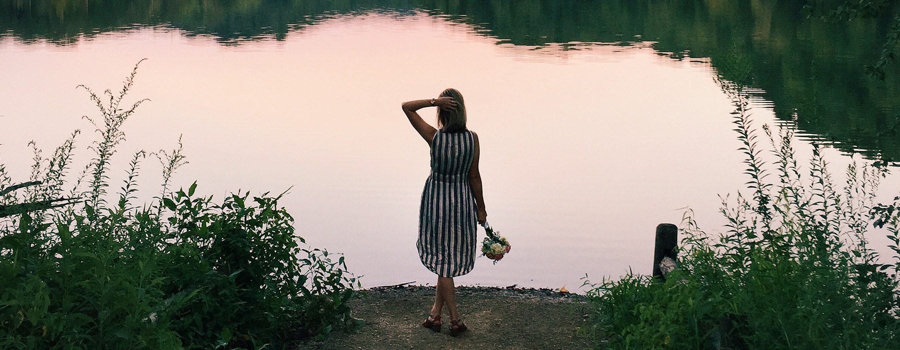 lifestyle image of a woman standing beside a body of water